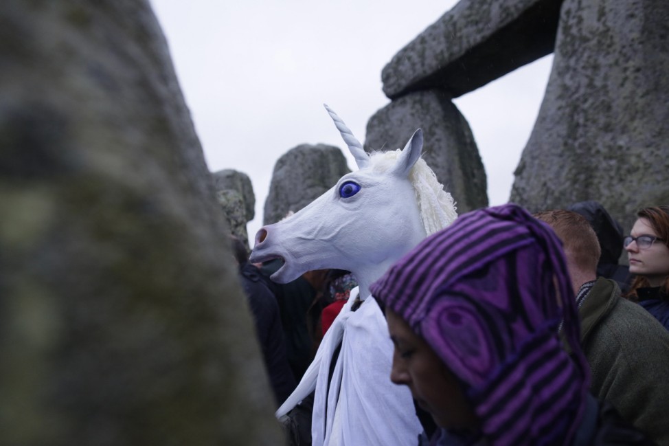 A reveller wearing a unicorn mask celebrates the winter solstice at Stonehenge in Amesbury, southern England