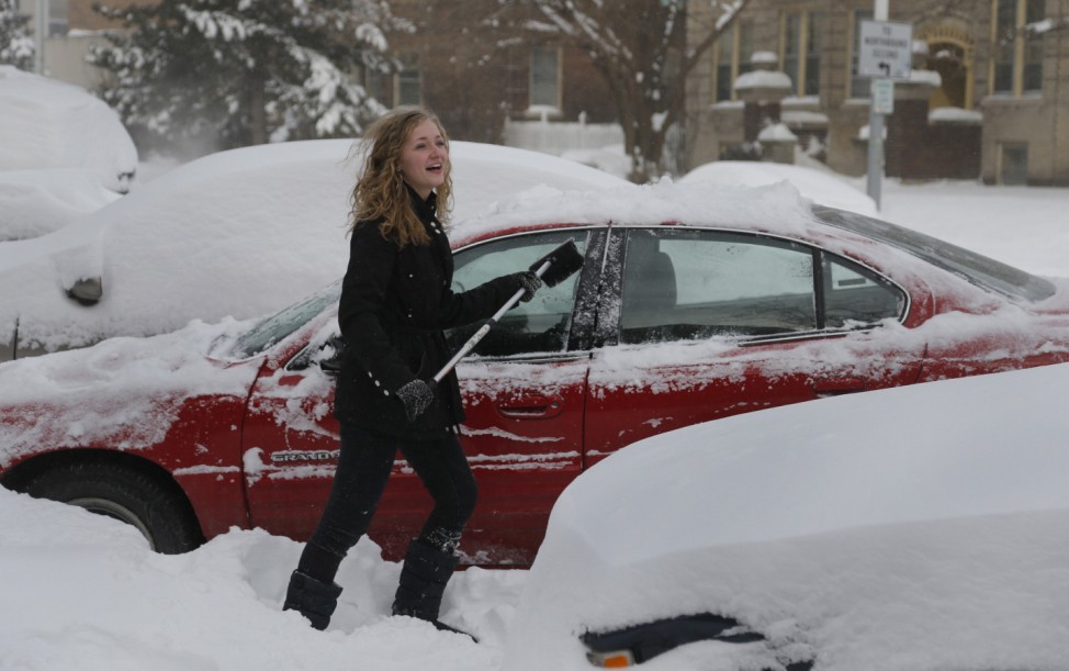 Grace Rogers cleans the snow off her car in the midtown neighborhood of Detroit