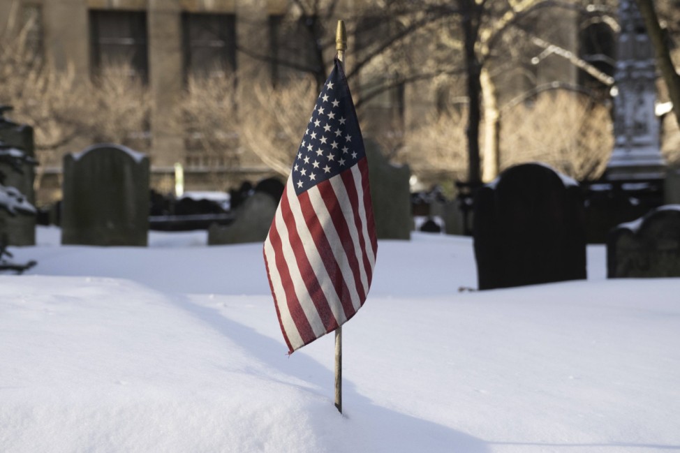 Snow lies around the U.S national flag at Trinity Church Cemetery during a winter storm in New York