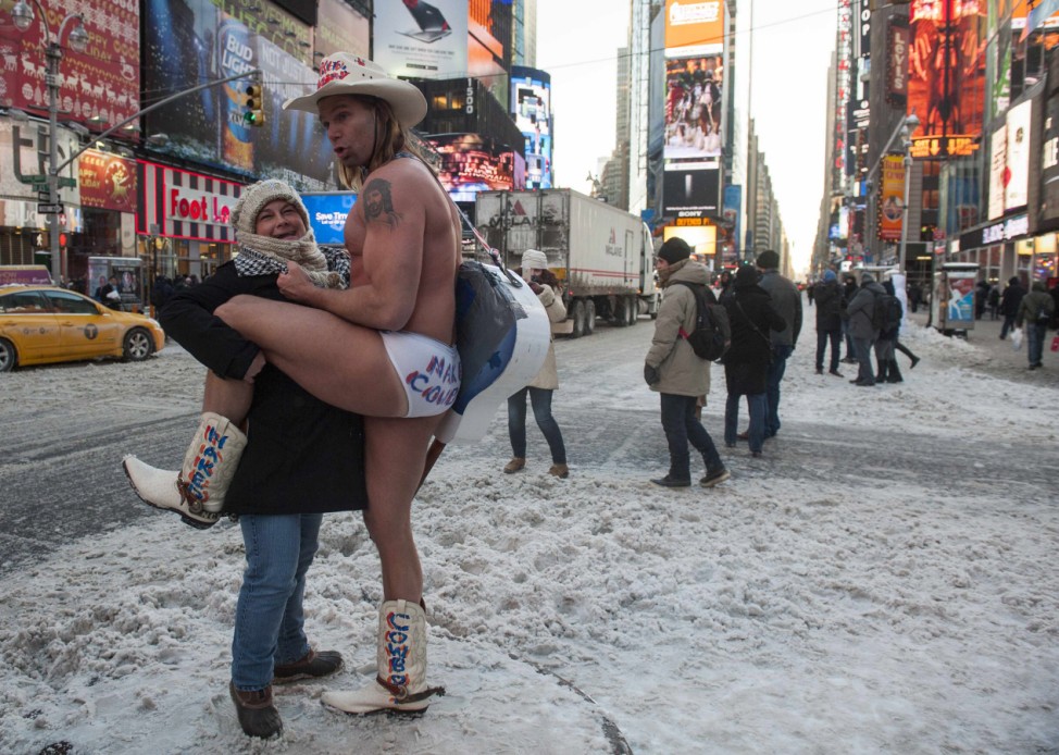 Robert Burck, also known as the original 'Naked Cowboy,'  poses with a woman after snowfall on the streets of Times Square, New York