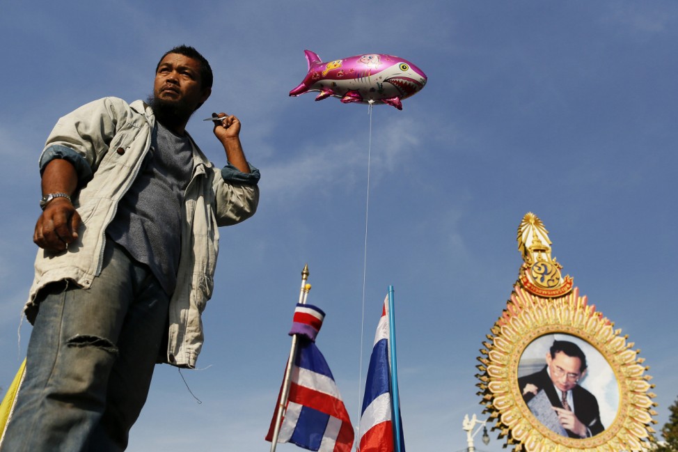 An anti-government protester combs his hair near the Democracy monument in Bangkok