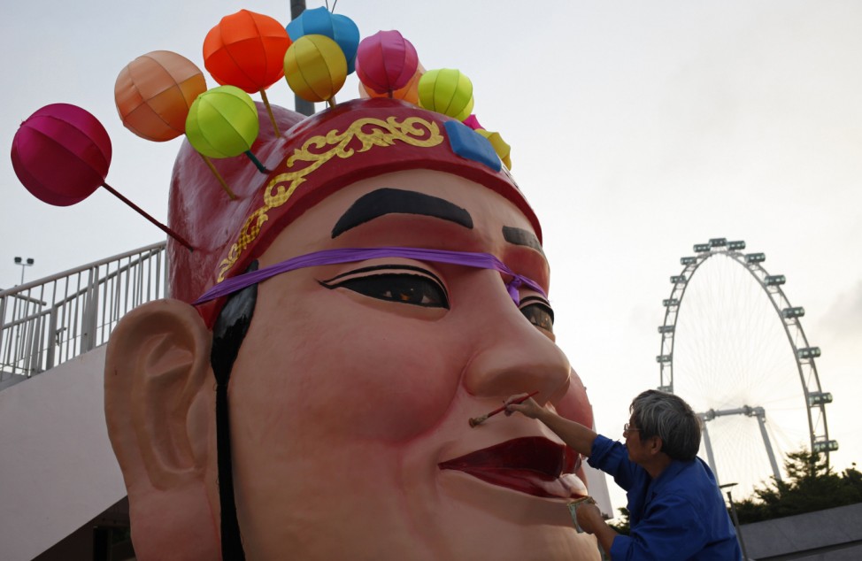 A craftsman paints the face of a God of Fortune statue as part of Chinese New Year decorations in Singapore