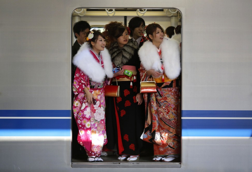 Japanese women in kimonos ride a train after a ceremony celebrating Coming of Age Day at an amusement park in Tokyo
