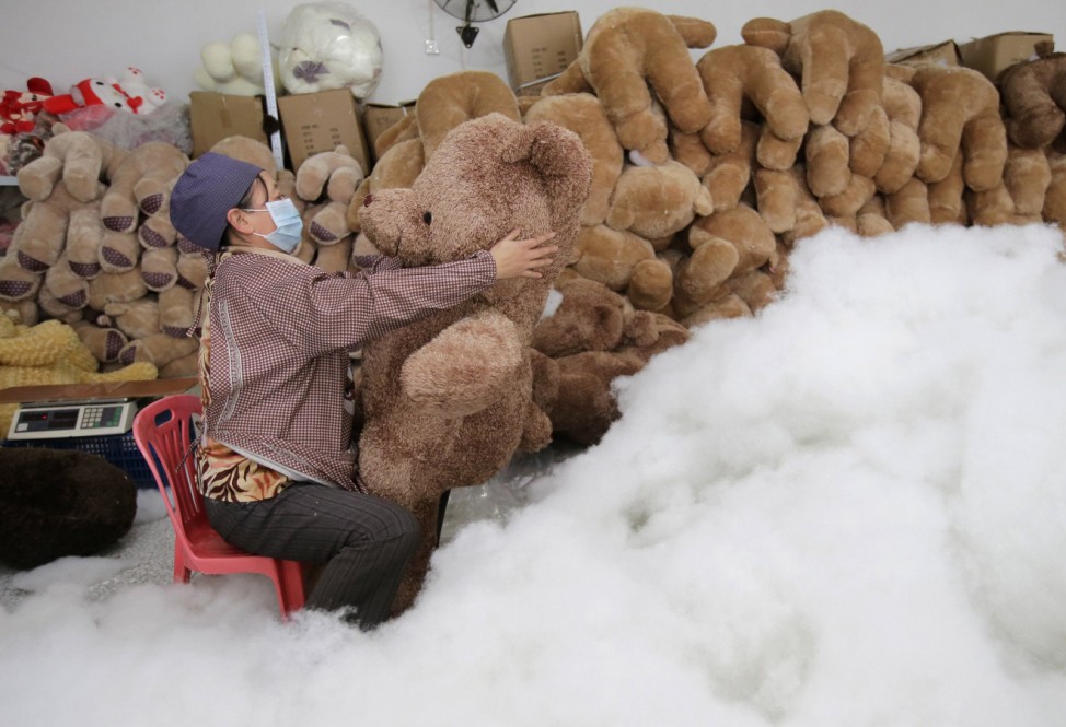 A worker stuffs a toy bear with cotton at a toy factory in Wuhan