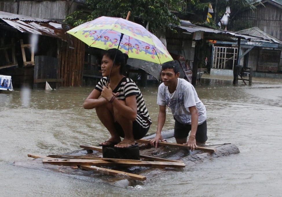 A resident on a makeshift raft navigates through floodwaters brought by tropical depression 'Agaton', along a road in Butuan
