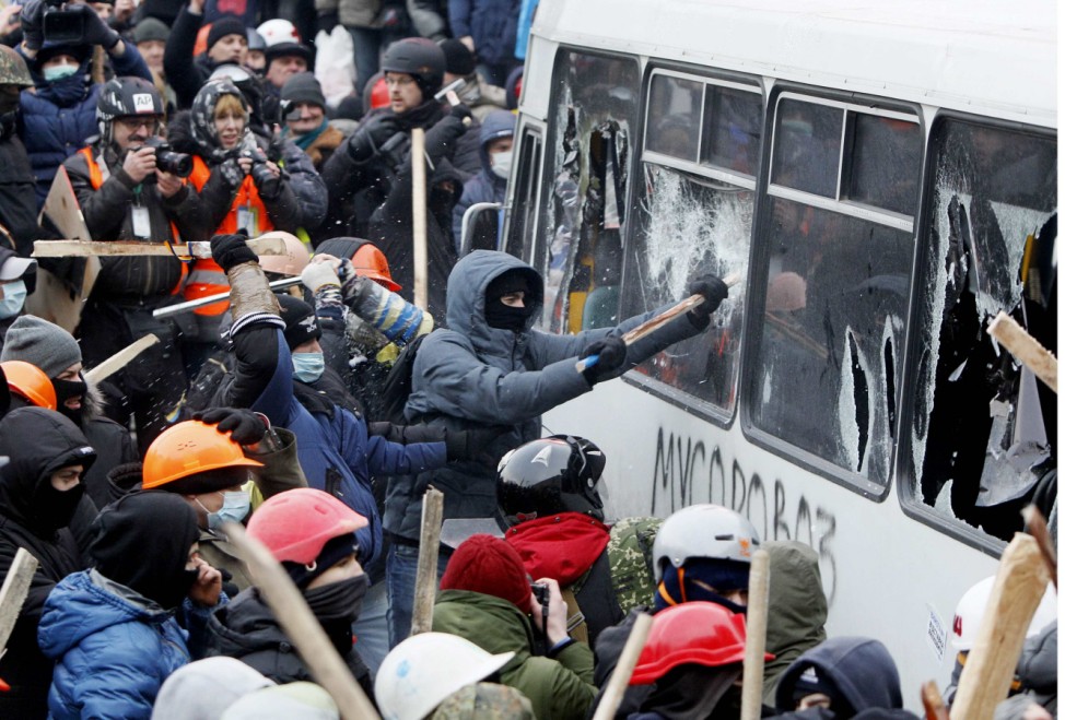 Pro-European protesters attack a police van during a rally near government administration buildings in Kiev