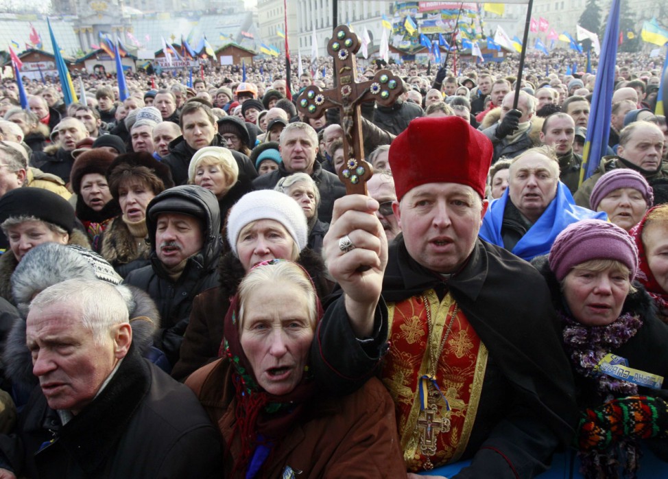 A priest holds a crucifix as he takes part in a pro-European rally on Independence Square in Kiev