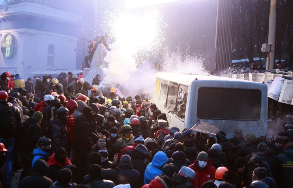 Pro-European integration protesters attack a police van during a rally near government administration buildings in Kiev