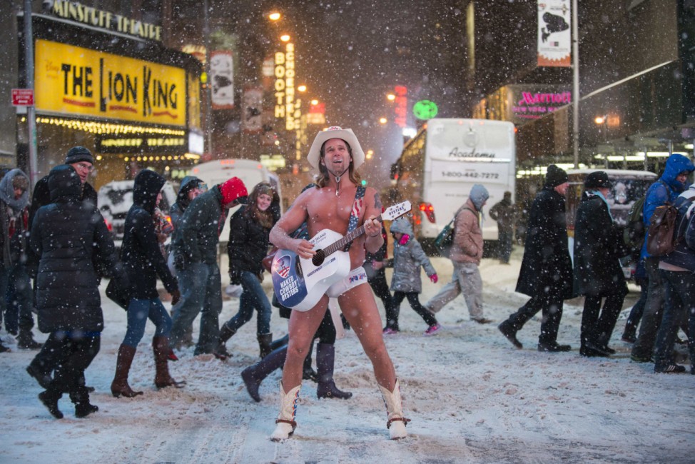 Robert Burck, also known as the original 'Naked Cowboy', performs in a snow storm on the streets of Times Square, New York
