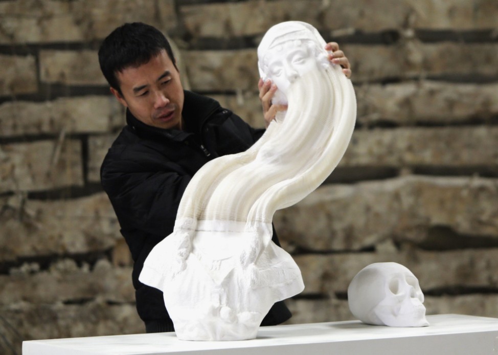 Chinese artist Li Hongbo stretches a paper sculpture work on the outskirts of Beijing