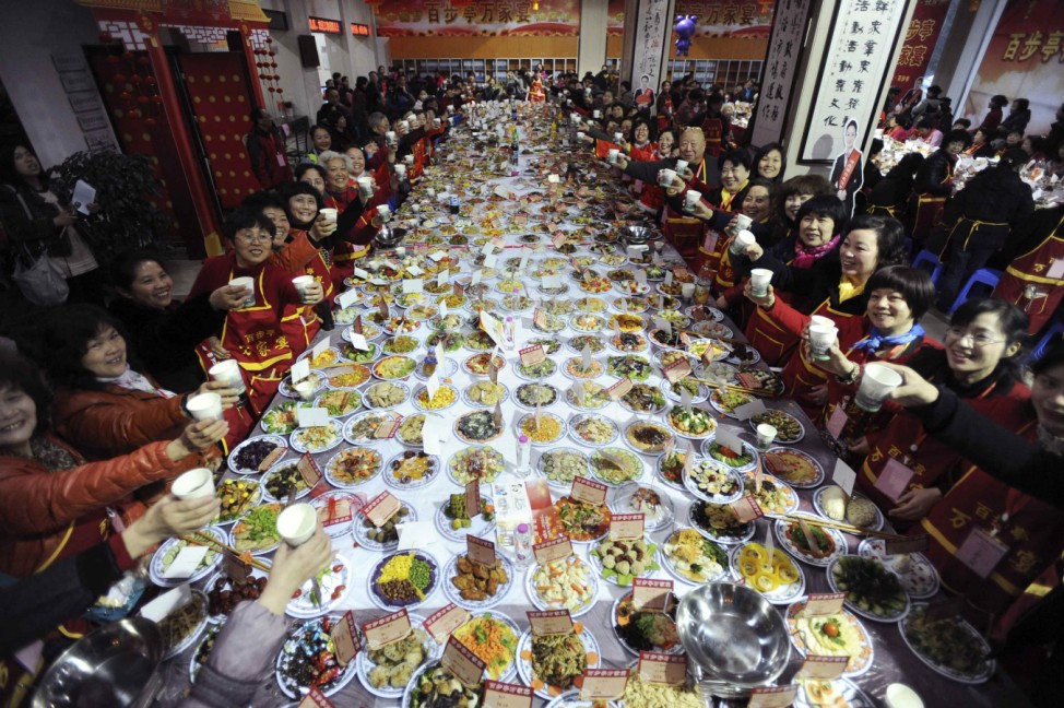 Residents raise their glasses as they pose for photographs during a 'Ten thousand families dinner' organized by a local community to celebrate the upcoming Chinese lunar new year in Wuhan