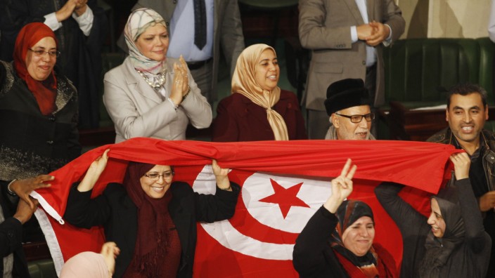 Members of the Tunisian parliament wave flags after approving the country's new constitution in the assembly building in Tunis