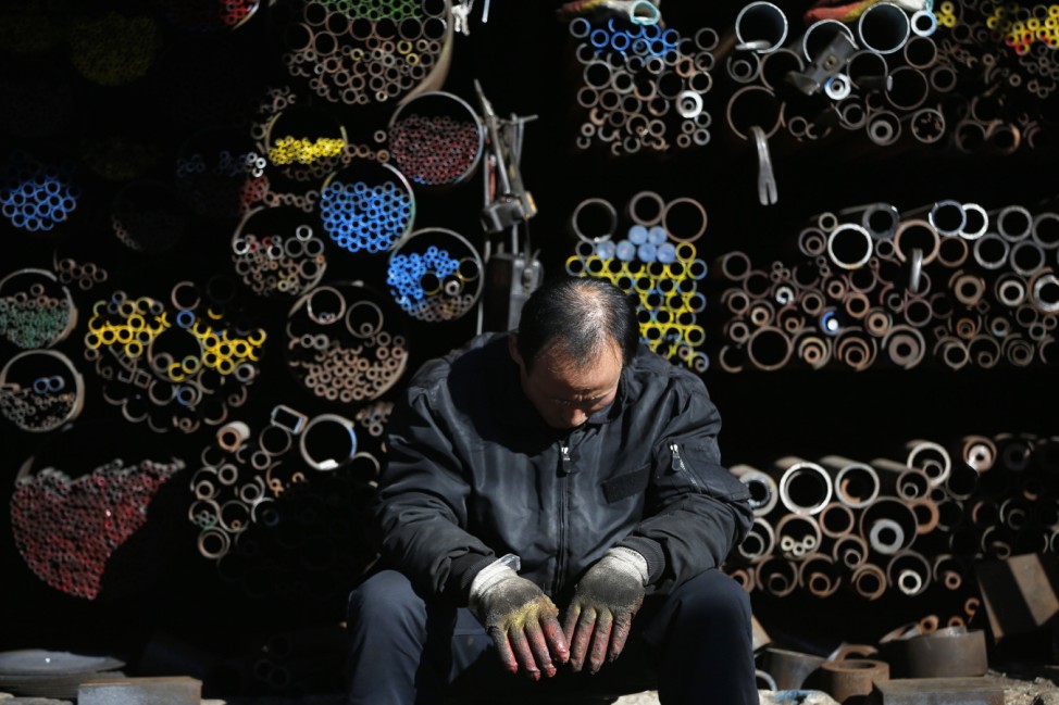 A worker takes a nap in front of steel products stacked at a steelworks in Seoul