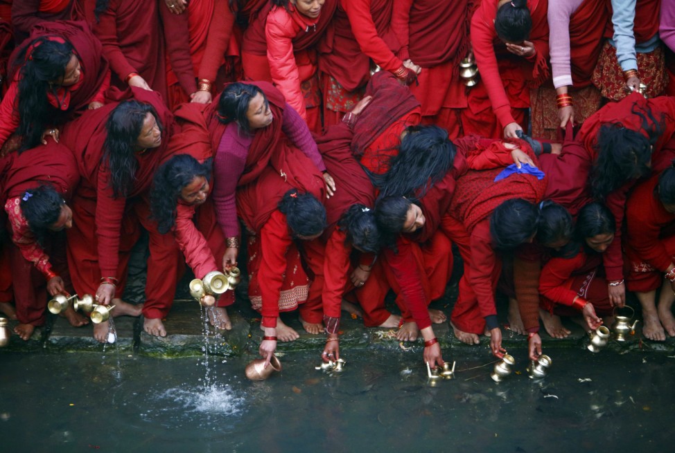Devotees fill their vessels with water, which is considered to be holy, from the Bagmati River at Pashupatinath Temple during the Swasthani Bratakatha festival in Kathmandu