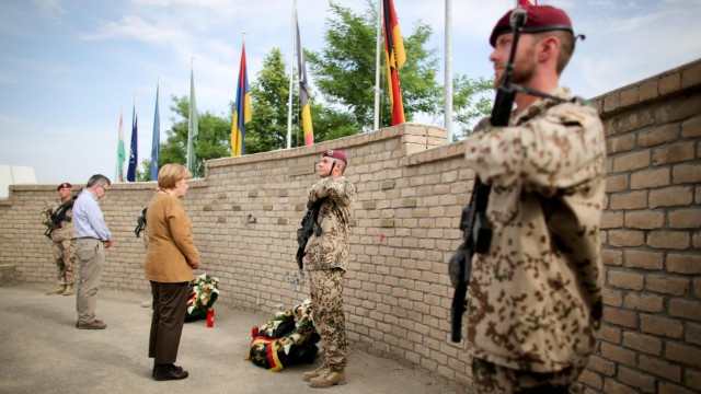 Bundeskanzlerin Angela Merkel und der damalige Verteidigungsminister Thomas de Maizière 2013 an der Gedenkstätte für in Afghanistan gestorbene Bundeswehrsoldaten im Basislager Kunduz