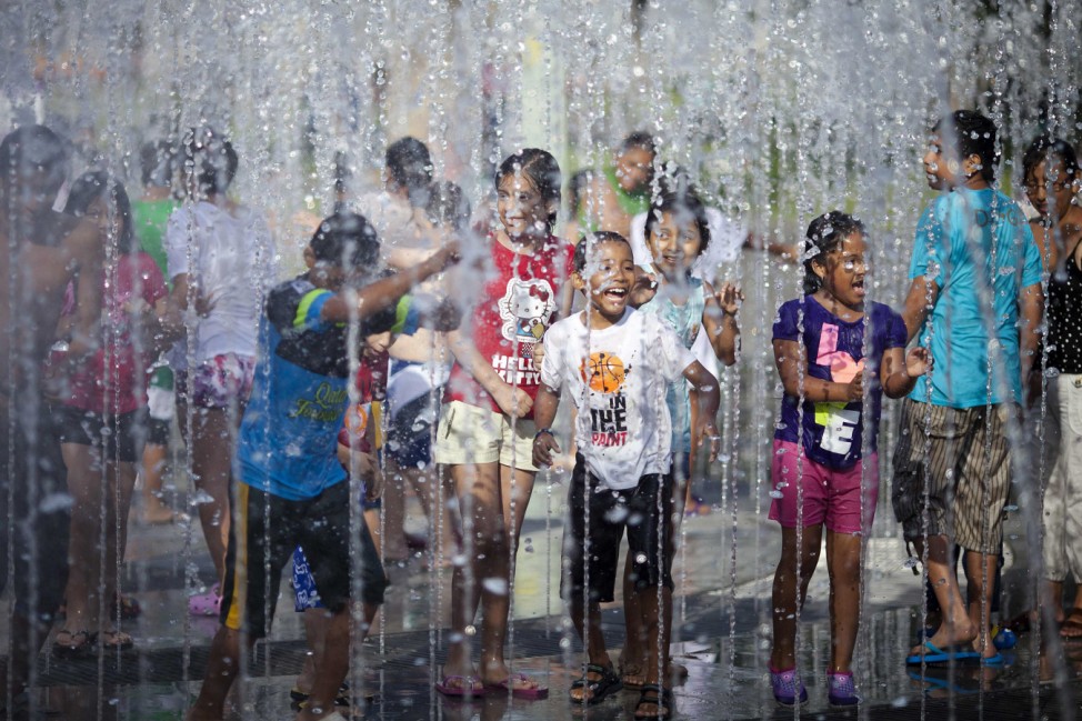 Children enjoy a water fountain during a summer day at the Exposition Park in downtown Lima