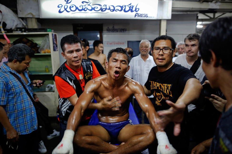 A fighter is helped after being defeated during the closing Thai boxing, or 'Muay Thai', fight night of the legendary Lumpinee stadium in Bangkok