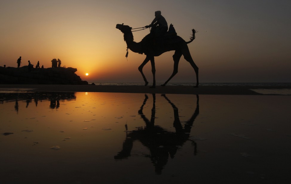 A Palestinian man rides a camel during sunset on the beach of Gaza City