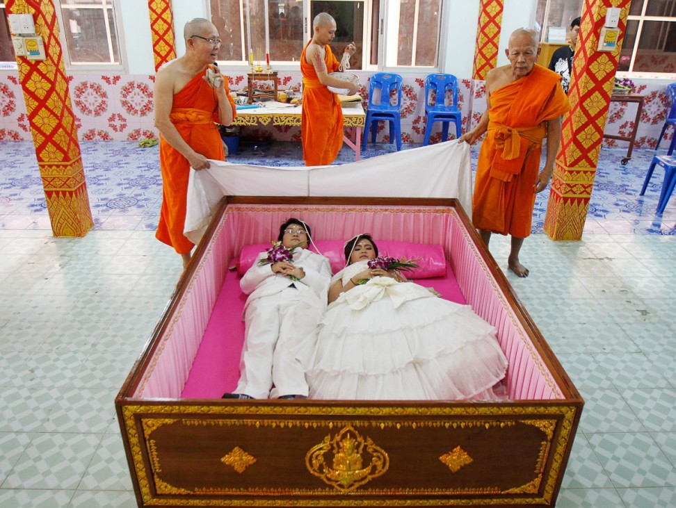 A couple lies in a coffin during a wedding ceremony at Wat Takien temple in Nonthaburi province