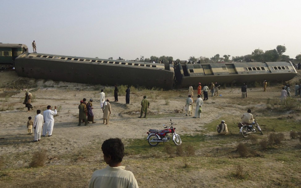 People gather at the site where a passenger train derailed after a blast in Pakistan's southern Kashmore district