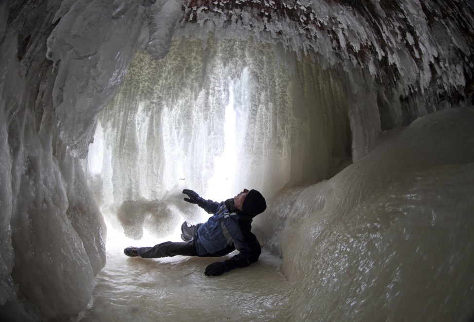 Man looks at ice formations in sea cave of the Apostle Islands National Lakeshore of Lake Superior