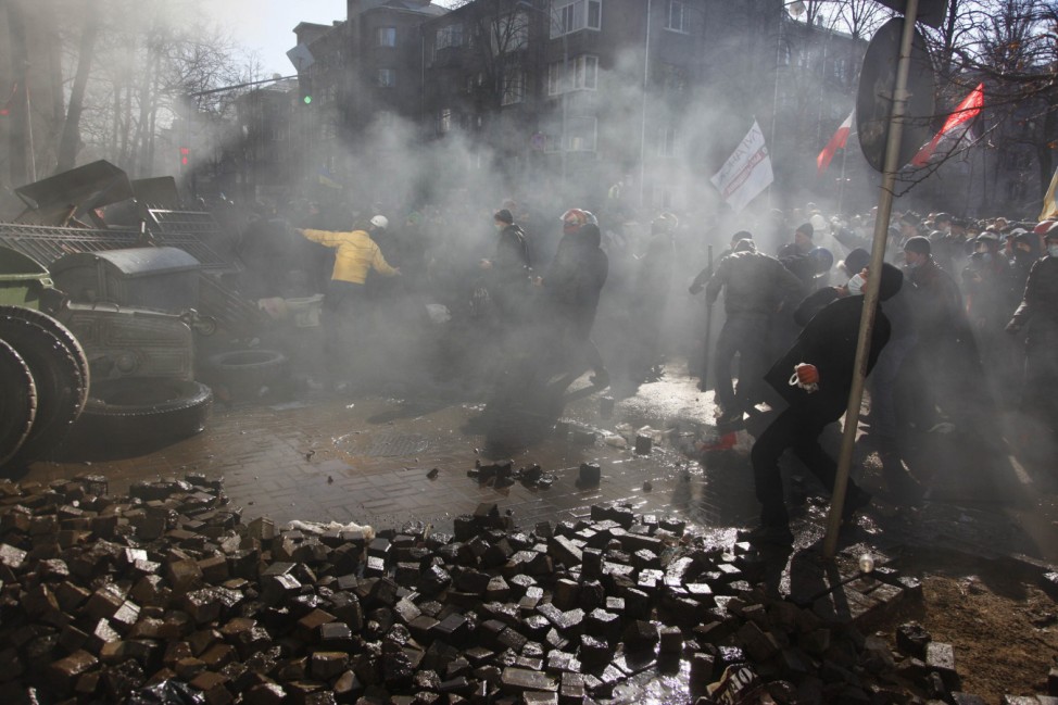 Anti-government protesters throw stones towards Interior Ministry officers during a rally in Kiev