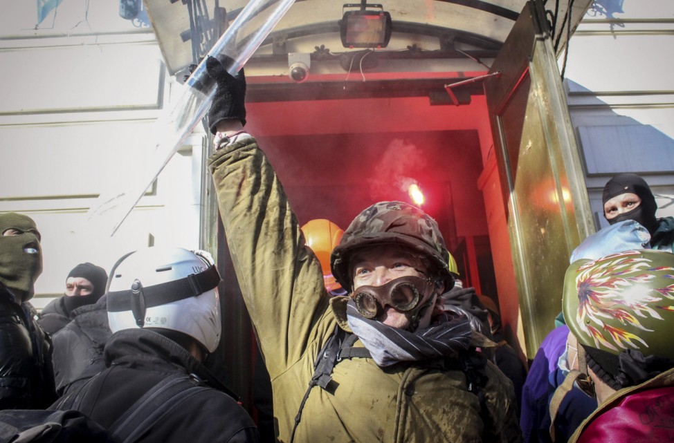 Anti-government protesters gather by the entrance as they attack an office of the pro-presidential Party of the Regions in Kiev