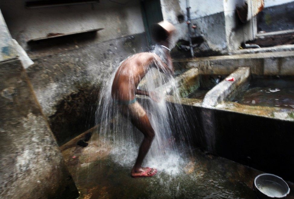 A man bathes in the early morning before the start of his day at a public well in Colombo