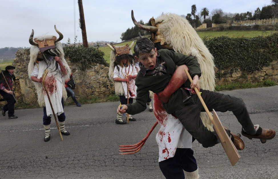A member of a folk group grabs a child during a parade, part of the VII Xornaes de Mazcares d'Inviernu (VII Winter Mask Meetings) in Valdesoto