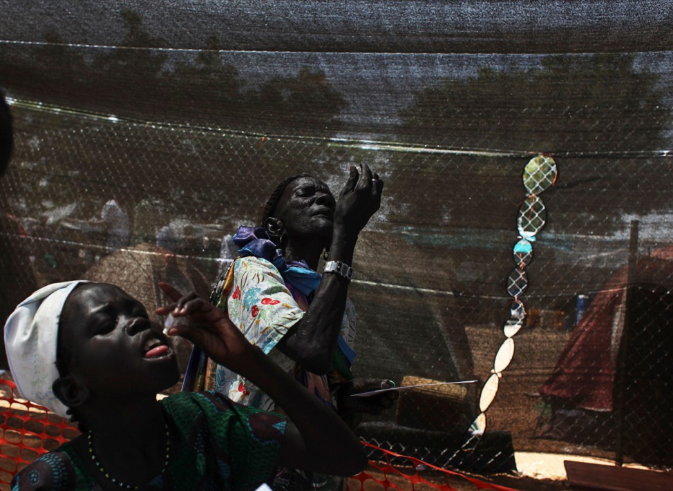 Displaced South Sudanese people administer oral cholera vaccines to themselves in a camp for internally displaced people in the UNMISS compound in Tomping