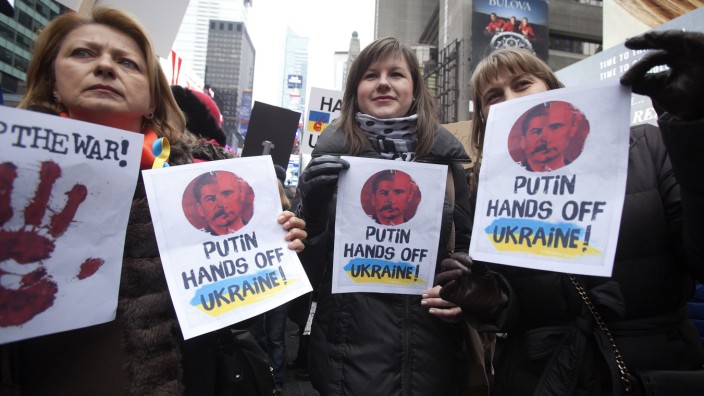 Women hold up signsduring a protest march in support of peace in the Ukraine in Times Square in New York