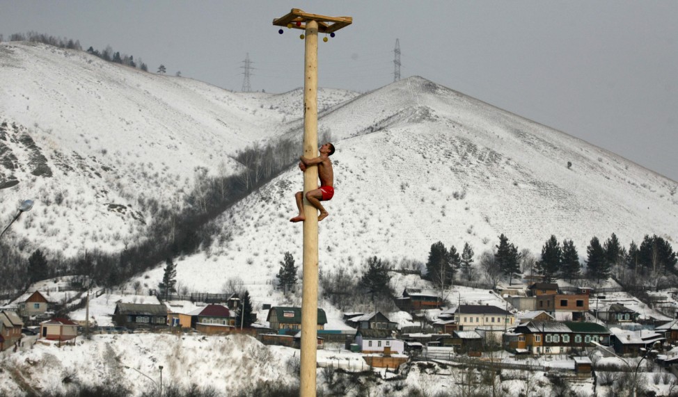 A man climbs up a smooth wooden column to win a contest during the celebrations of Maslenitsa, or Pancake Week, in Krasnoyarsk