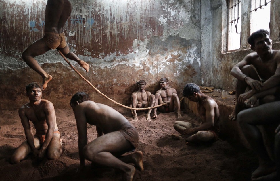 Wrestlers practise as others rest in the mud at a traditional Indian wrestling centre called Akhaara in Mumbai