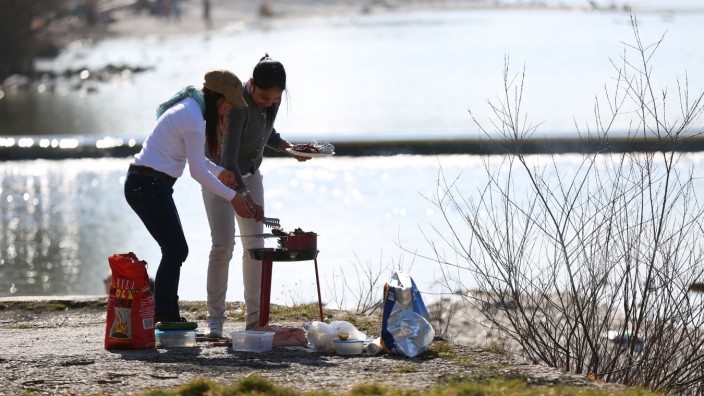 Typisch deutsch: Zwei junge Frauen grillen an einem warmen Tag in der Nähe des Flauchers an der Isar.