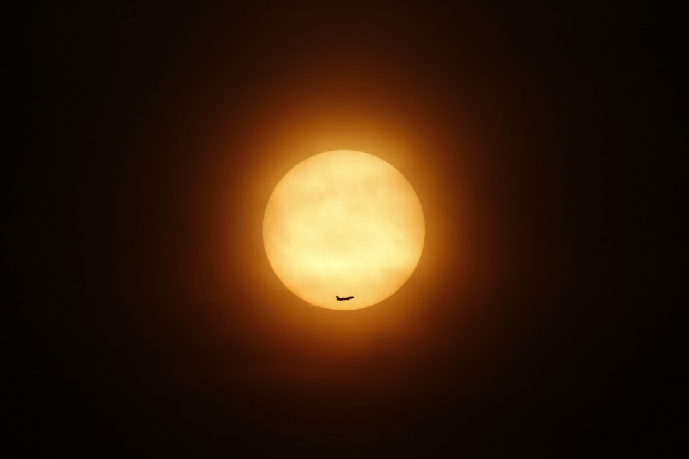 A passenger jet flies past the setting sun in Shanghai