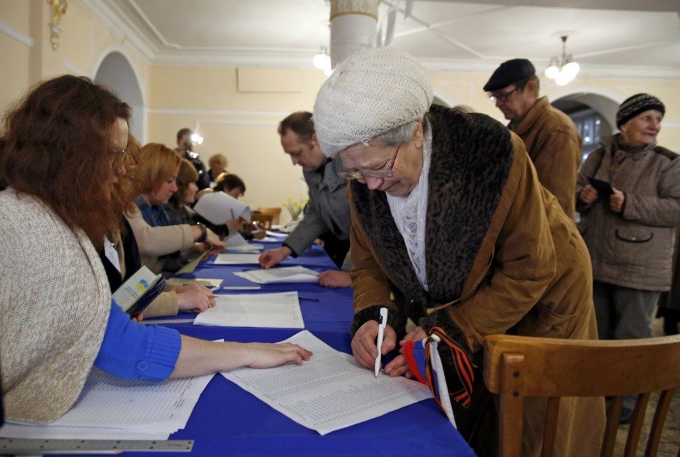 A woman holds a Russian flag as she signs to receive her ballot during the referendum on the status of Ukraine's Crimea region at a polling station in Sevastopol
