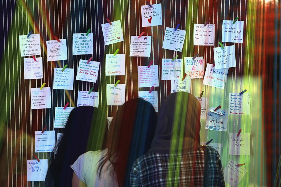 Women look at messages and well-wishes for family members of passengers onboard the missing Malaysia Airlines Flight MH370 at an event to express solidarity in Subang Jaya