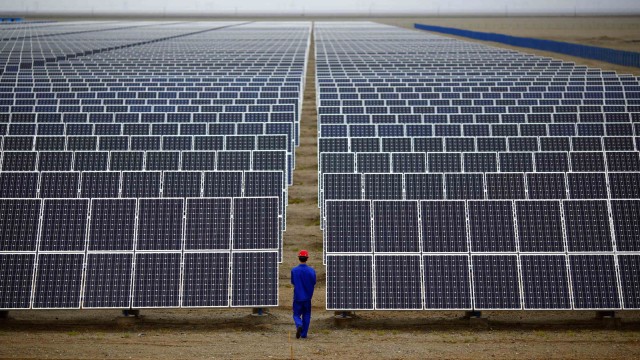 File photo of worker inspecting solar panels at a solar farm in Dunhuang