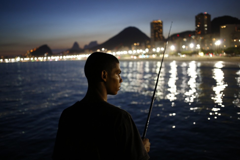 A fisherman waits for a catch in front of the beach of Copacabana in Rio de Janeiro
