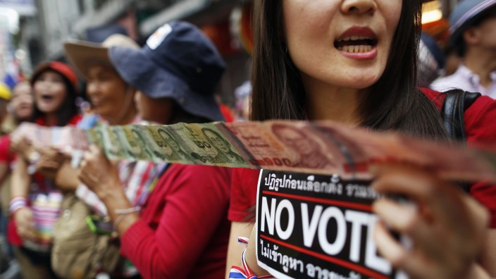 Anti-government protesters hold 'No Vote' stickers and Thai baht banknotes to donate to leader during march in Bangkok