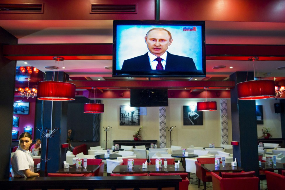 A staff watches a speech given by Russian President Vladimir Putin in a cafe in Simferopol