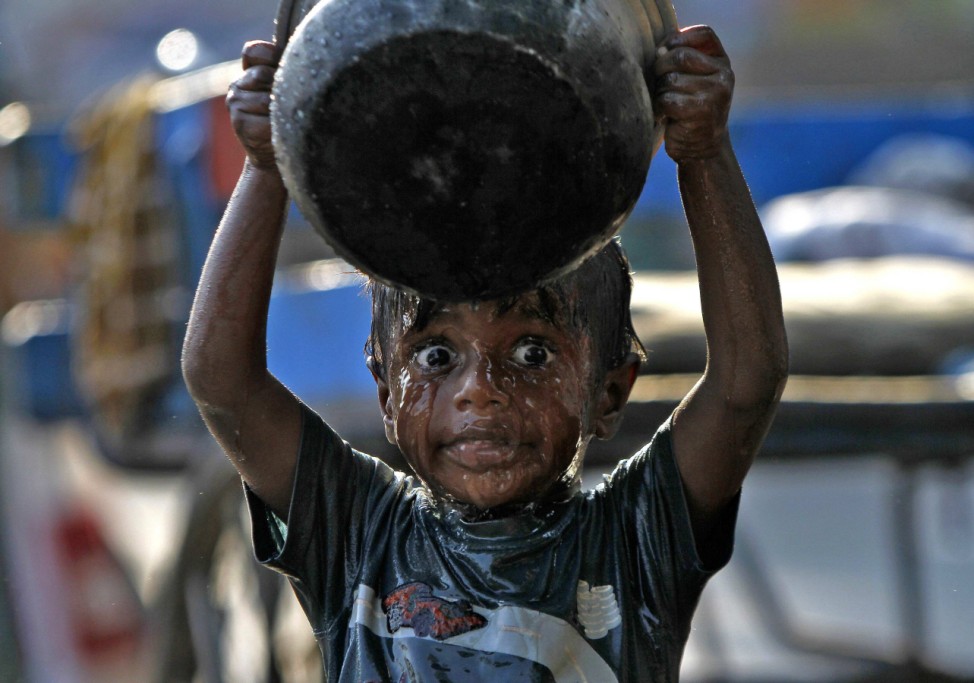 A boy takes a bath along a pavement in Chennai