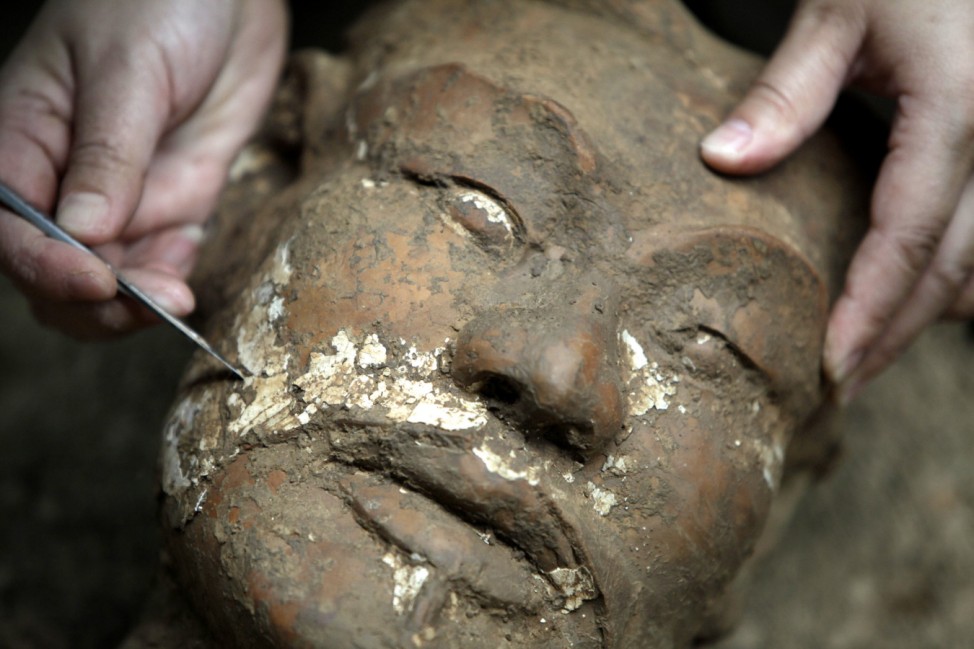 An archaeologist removes earth from the face of a newly found terracotta warrior at the excavation site on the outskirts of Xi'an