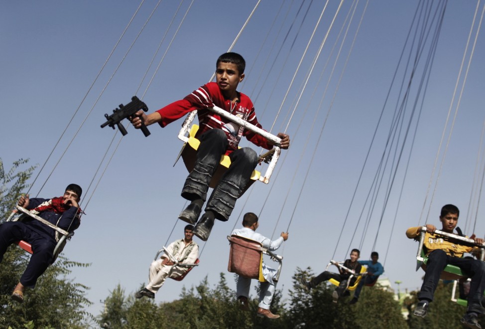 An Afghan boy holds a toy gun as he enjoys a ride with others on a...