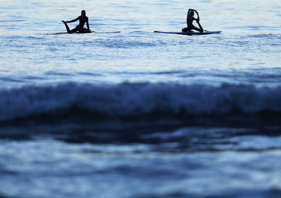 Twelve-year-old certified yoga instructor Jaysea DeVoe does the mermaid pose with her friend Miely as they float on their paddle boards after the sun sets in Encinitas, California