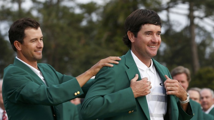 Masters champion Watson is helped with his traditional green jacket by last year's champion Scott of Australia after the final round of the Masters golf tournament at the Augusta National Golf Club in Augusta