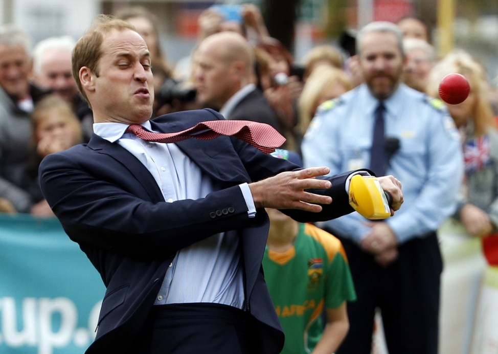 Britain's Prince William reacts as he tries to hit a ball using a cricket bat as he and his wife Catherine, the Duchess of Cambridge, attend a promotional event for the upcoming Cricket World Cup in Christchurch