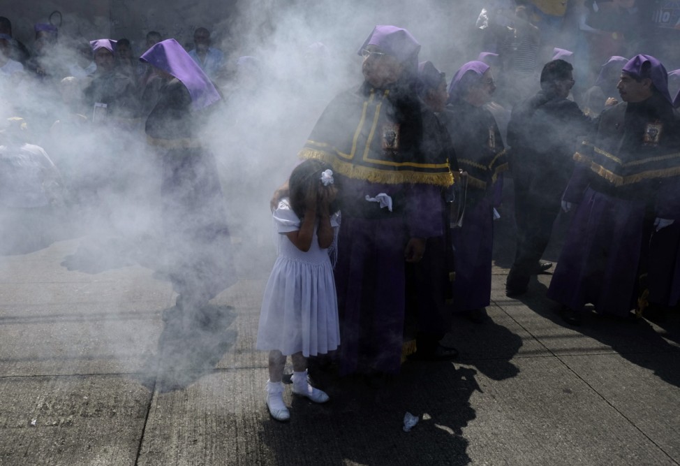 Ein Kind in Guatemala Stadt bedeckt sein Gesicht, während es von Weihrauch-Schwaden eingehüllt wird