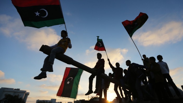 Boys carrying flags sit on a tank in Benghazi  during the third anniversary of an attack by pro-Gaddafi forces on Benghazi
