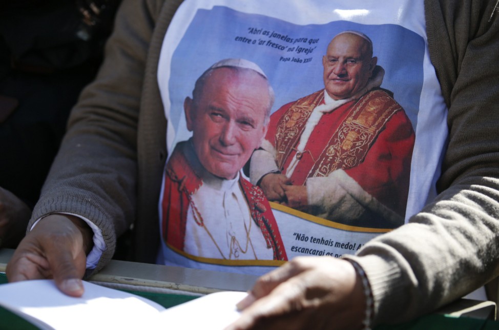 A faithful wears a t-shirt depicting the late Pope John Paul II and Pope John XXIII as Pope Francis leads the Easter Mass in Saint Peter's Square at the Vatican